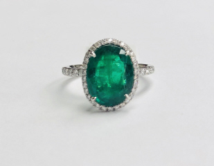 Platinum emerald and diamond halo style ring.