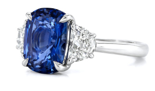Platinum cushion cut sapphire and half moon diamond 3-stone ring.